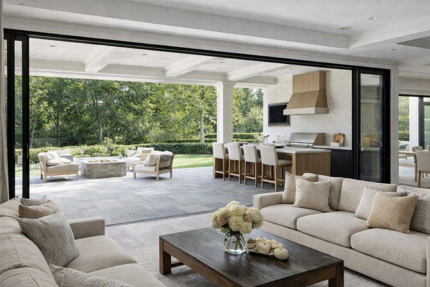 Seamless indoor-outdoor entertaining space with open living room, large sliding doors, and outdoor kitchen designed for gathering