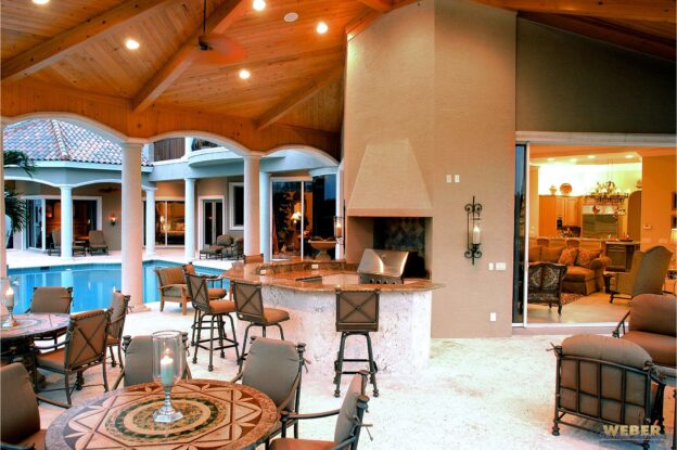 Holiday-ready outdoor living space with covered lanai, outdoor kitchen, fireplace, and seamless indoor-outdoor entertaining layout